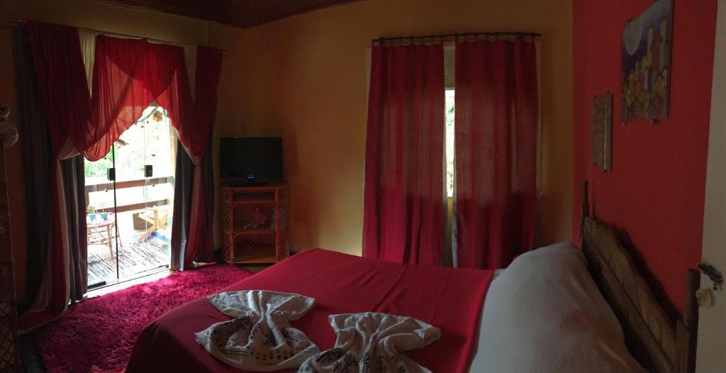 a bedroom with a bed with red curtains and a window at Loft Cravo & Canela in São Pedro da Serra