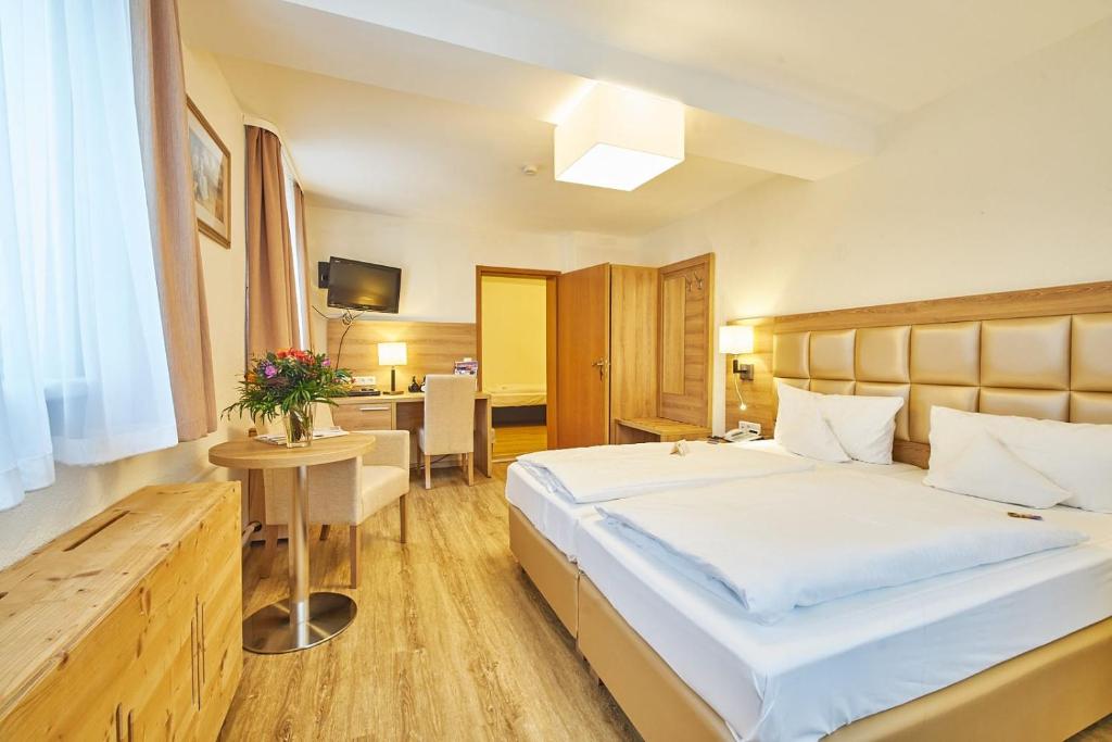 a hotel room with a bed and a dining room at Akzent Hotel Goldner Stern in Muggendorf