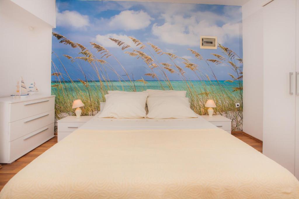 a bedroom with a bed with a painting of a beach at Apartments Marina in Šibenik