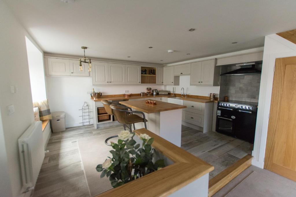 a kitchen with white cabinets and a black appliances at Bakers Cottage in Cockermouth