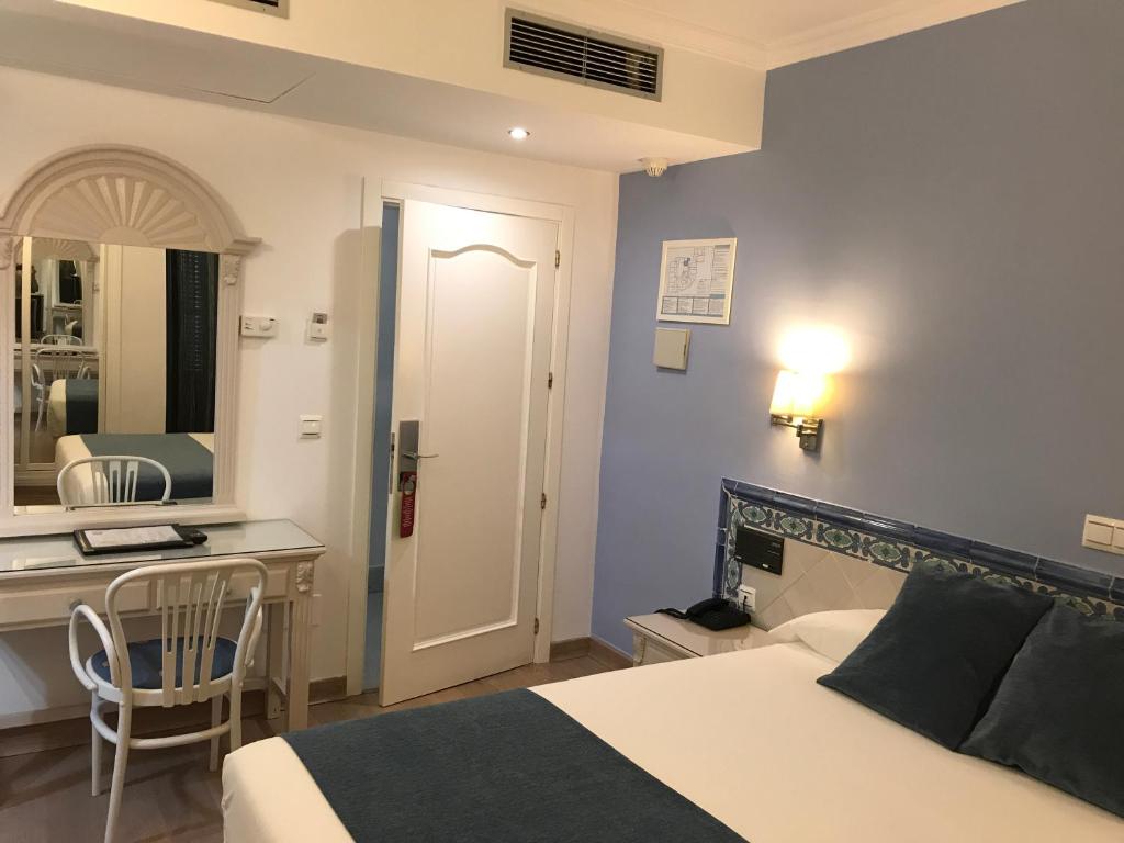 a bedroom with a bed and a desk and a sink at Hotel Plaza Cavana in Nerja