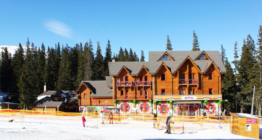 a large wooden ski lodge with people in the snow at Янтри in Dragobrat