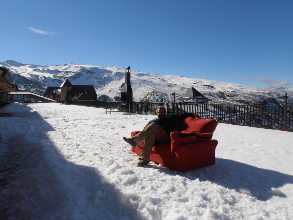シエラネバダにあるSierra Nevada Junto Remontesの雪の中の赤いソファに座っている男