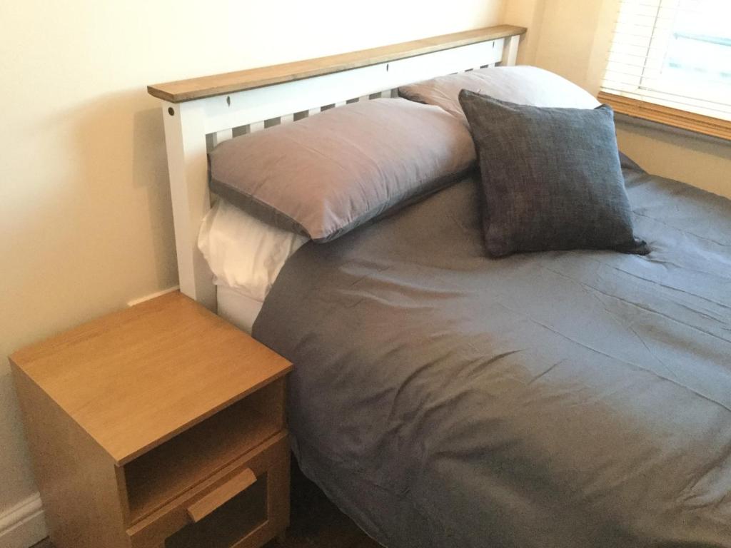 a bed with a wooden headboard and a night stand at Modern Luxury Central Apartment in Birmingham