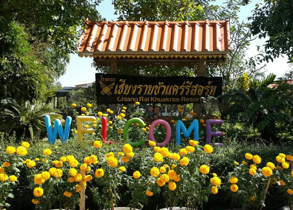 a sign for the chinese new year in a garden of flowers at Chiang Rai Khuakrae Resort in Chiang Rai