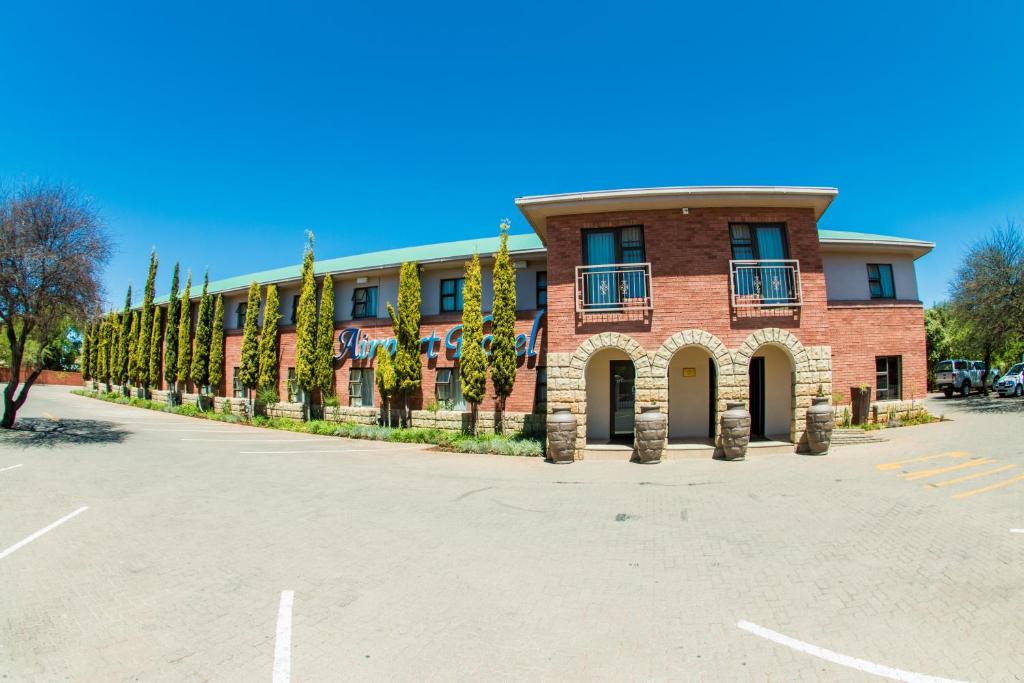 a large brick building with trees in front of it at Airport Hotel in Kimberley