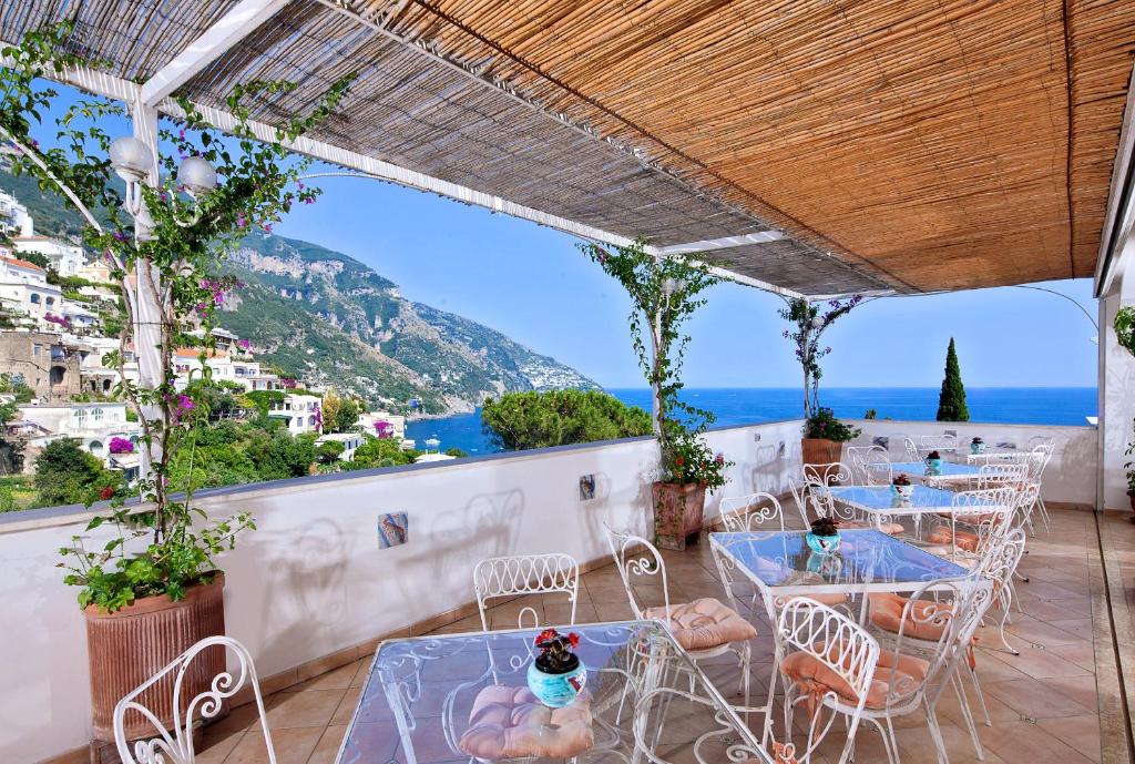 un patio con tavoli, sedie e vista sull'oceano di Hotel Vittoria a Positano