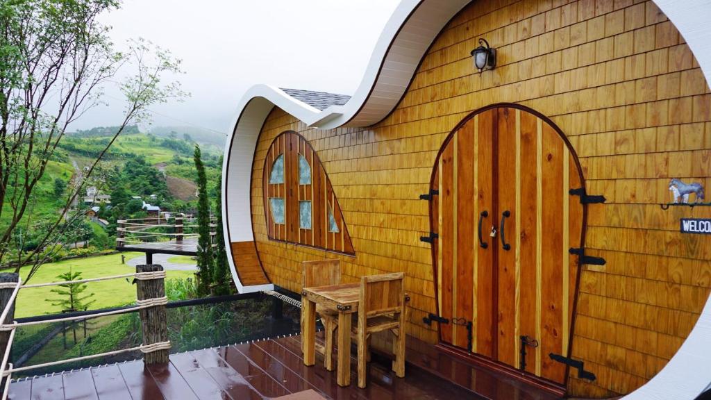 ein kleines Holzgebäude mit zwei Türen und einem Tisch in der Unterkunft Kiri Pura Resort in Khao Kho