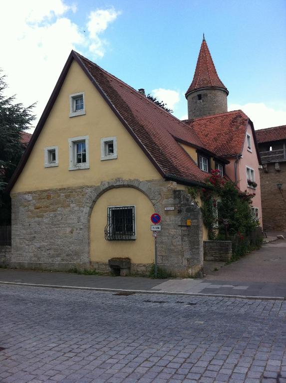 a yellow building with a red roof on a street at Pension Freund in Rothenburg ob der Tauber