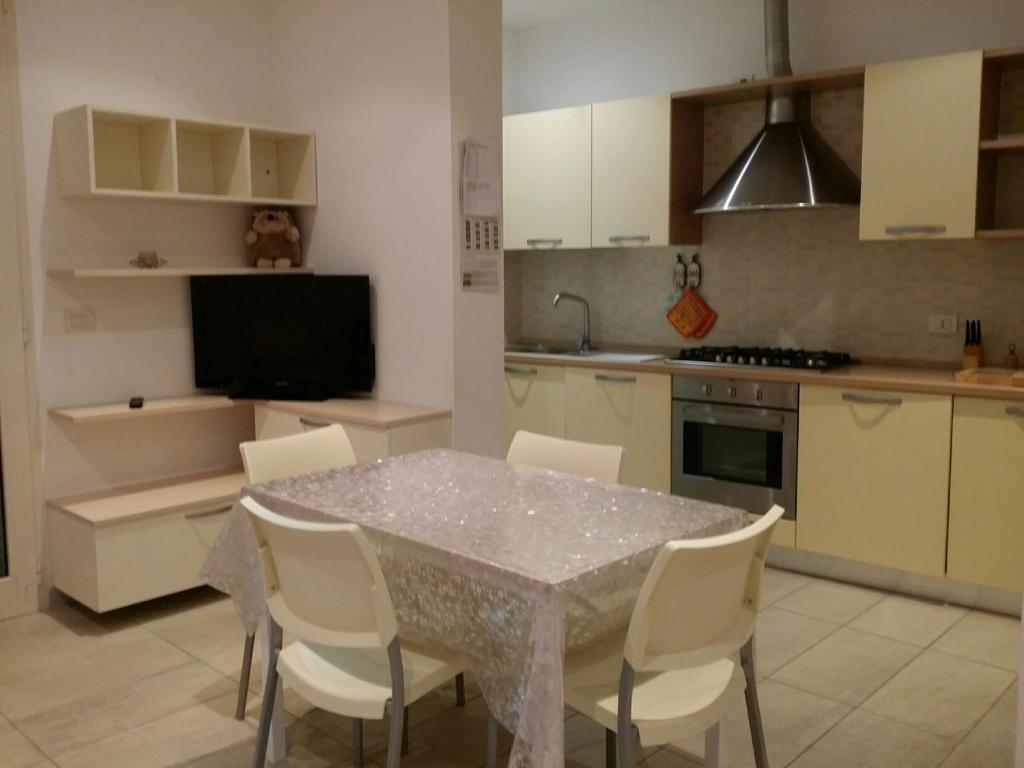 ベッラーリア・イジェア・マリーナにあるGianfrancaのキッチン(テーブル、白い椅子、テレビ付)