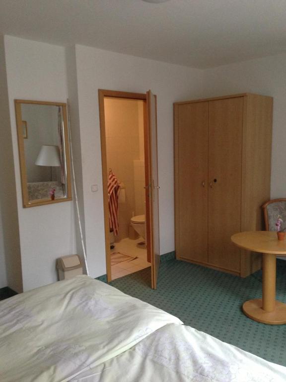 a bedroom with a bed and a table and a mirror at Pension Freund in Rothenburg ob der Tauber