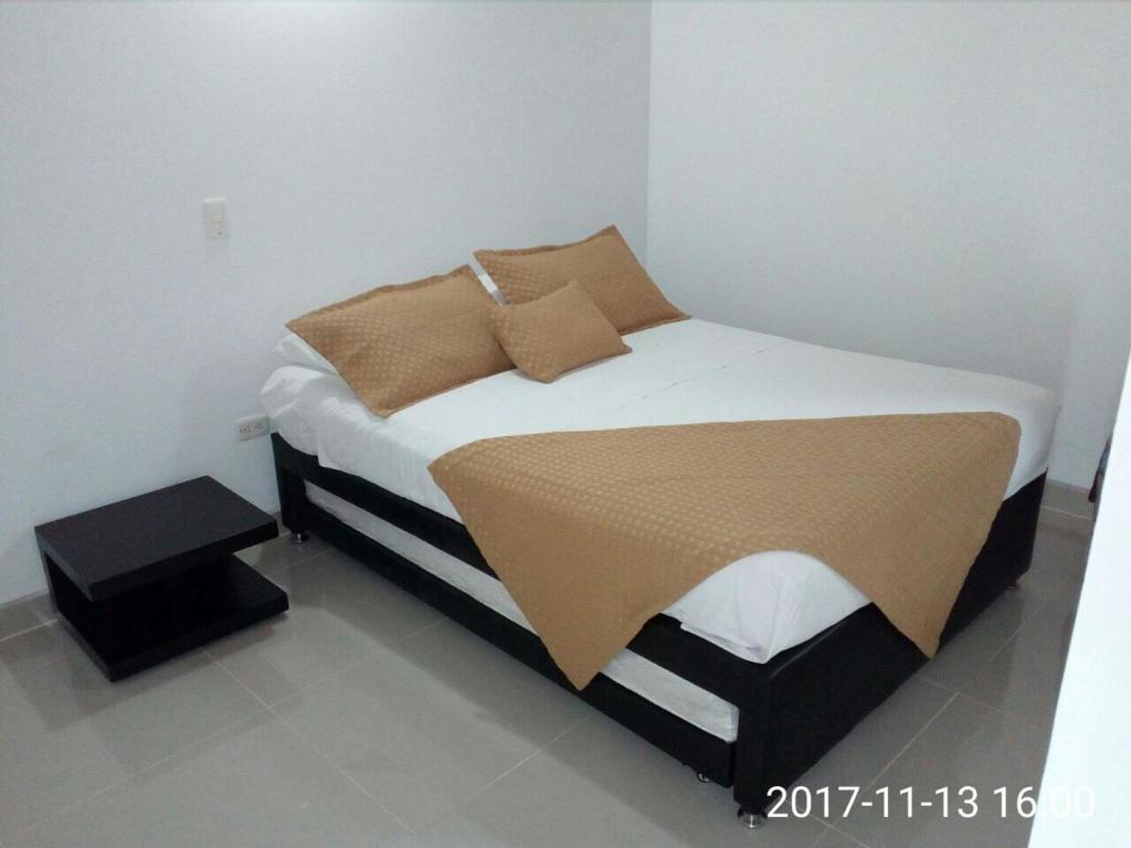 a bedroom with a bed with white sheets and brown pillows at Jardín Amoblados in Jardin