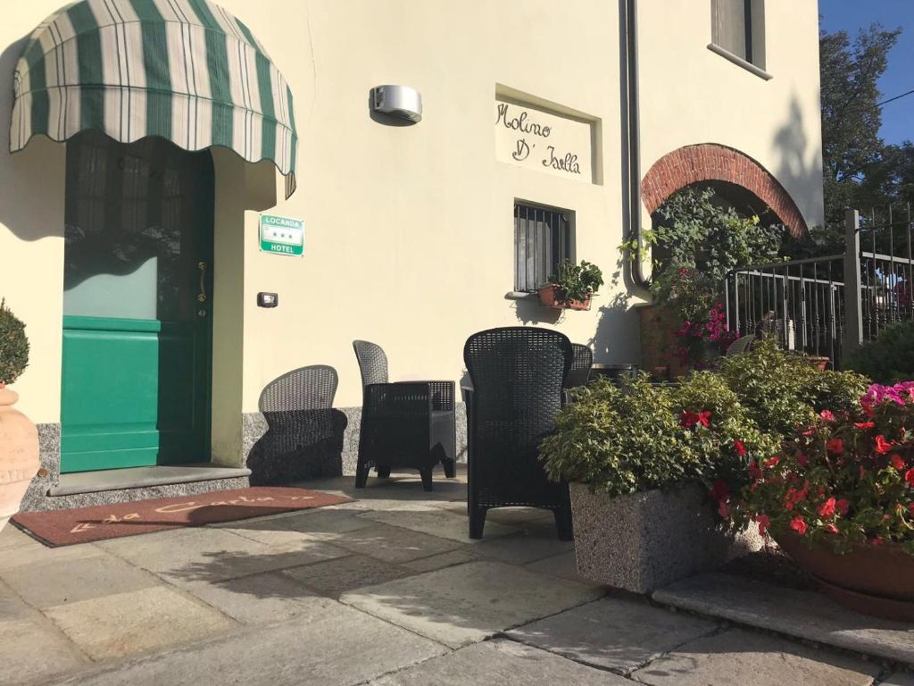 ヴィジェーヴァノにあるHotel Locanda Da Carlaの建物の前に椅子と花が並ぶパティオ