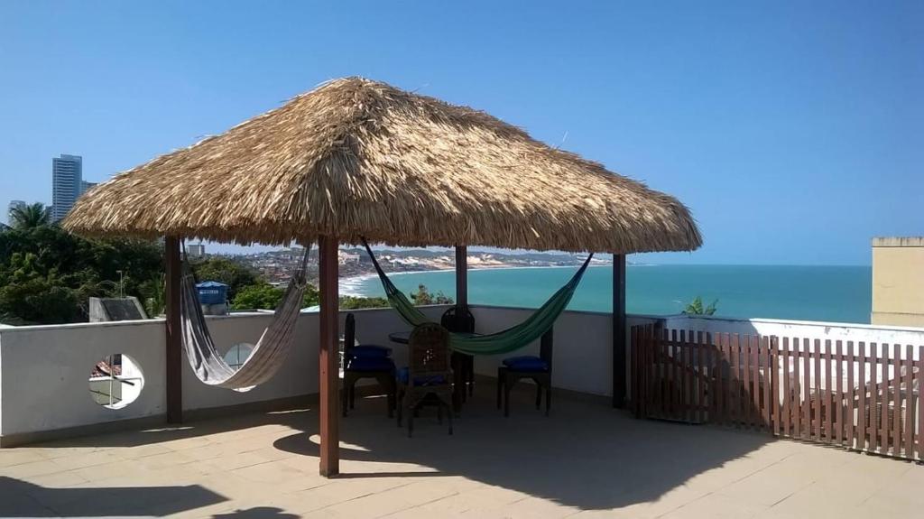 a patio with hammocks and a straw umbrella at Mariner Apartamentos in Natal