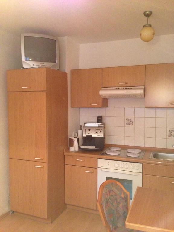 a kitchen with wooden cabinets and a tv on top at Pension Freund in Rothenburg ob der Tauber