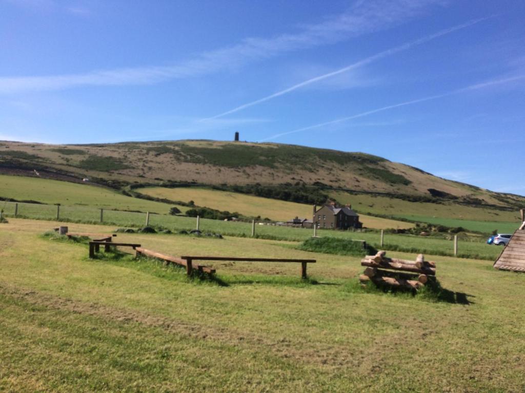 a field with benches and a hill in the background at Knockaloe Beg Farm in Patrick