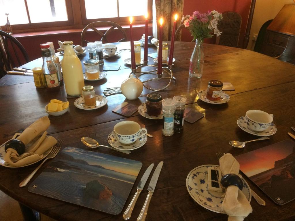 a wooden table with plates and cups and a vase at Knockaloe Beg Farm in Patrick