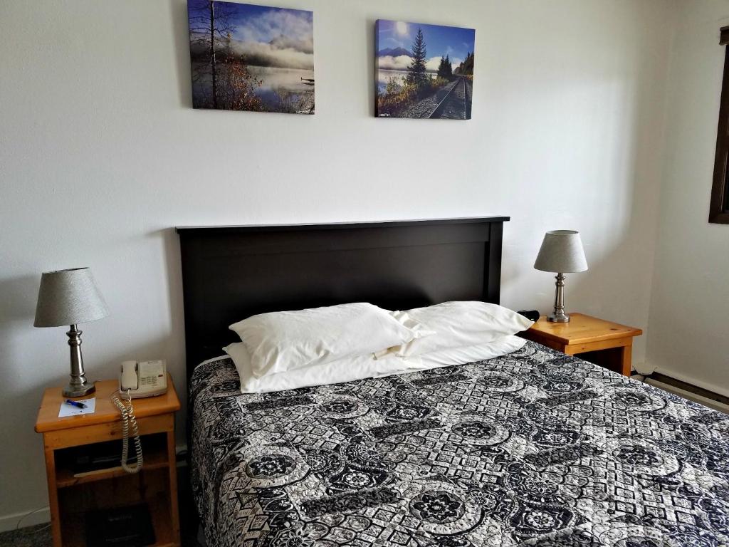 ein Schlafzimmer mit einem Bett mit zwei Lampen und zwei Tischen in der Unterkunft Soldotna Inn in Soldotna