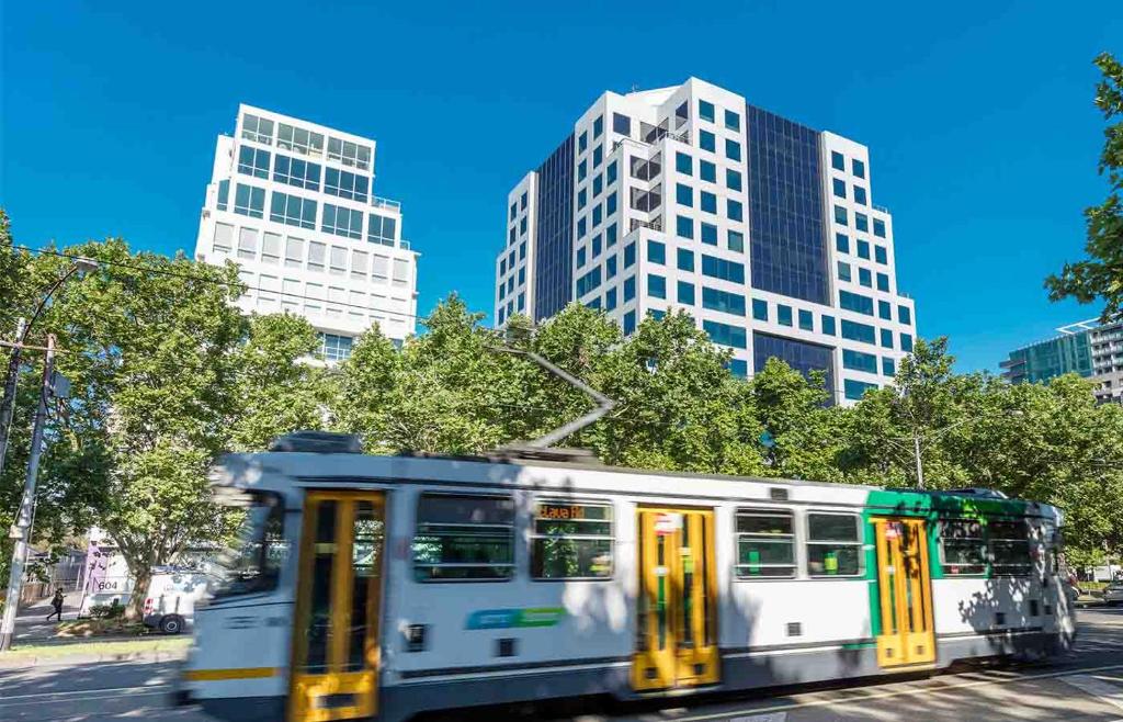 um autocarro a descer uma rua com edifícios altos em Park Regis Griffin Suites em Melbourne