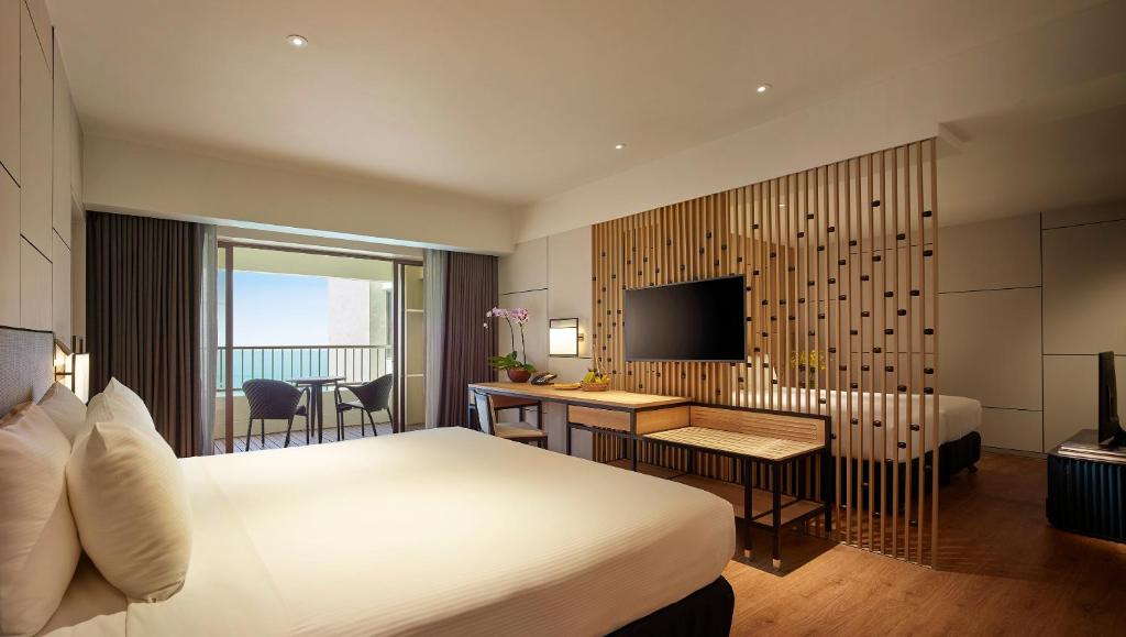 a hotel room with a bed and a desk and a television at PARKROYAL Penang Resort in Batu Ferringhi