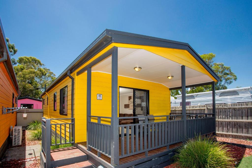 a yellow tiny house with a train in the background at BIG4 Traralgon Park Lane Holiday Park in Traralgon