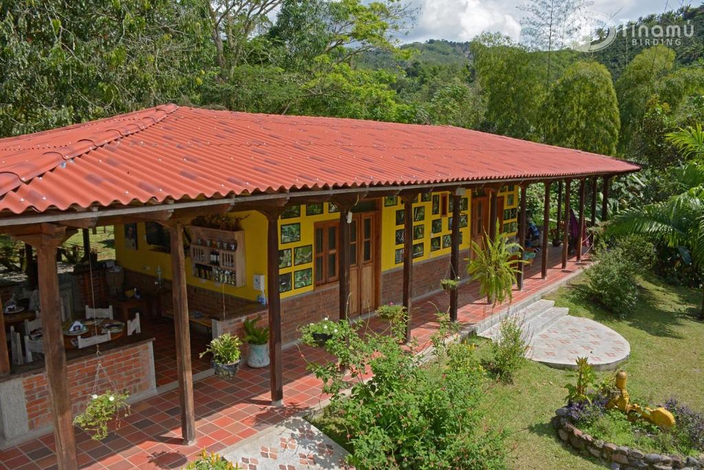 una pequeña casa amarilla con techo rojo en Tinamu Birding en La Manuelita