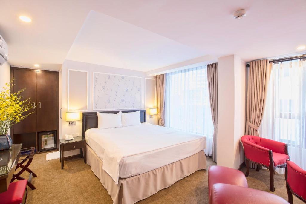 a hotel room with a large white bed and red chairs at Dinh Ami Hanoi Hotel in Hanoi