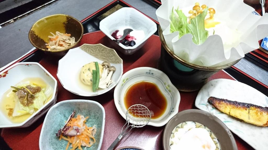 una tavola con piatti di cibo su un tavolo di Onyado Hishiya Torazo a Yamanouchi