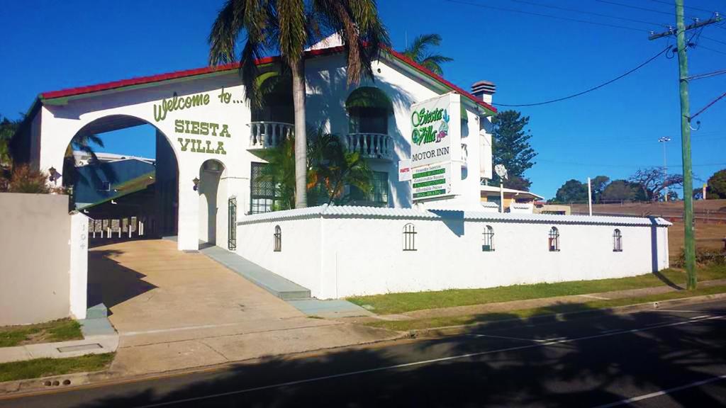 a white building with an archway on a street at Siesta Villa Motel in Gladstone