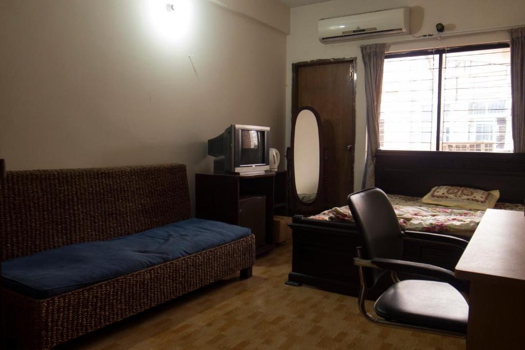 a room with a bed and a chair and a tv at Japanese lodge hydrangea in Dhaka