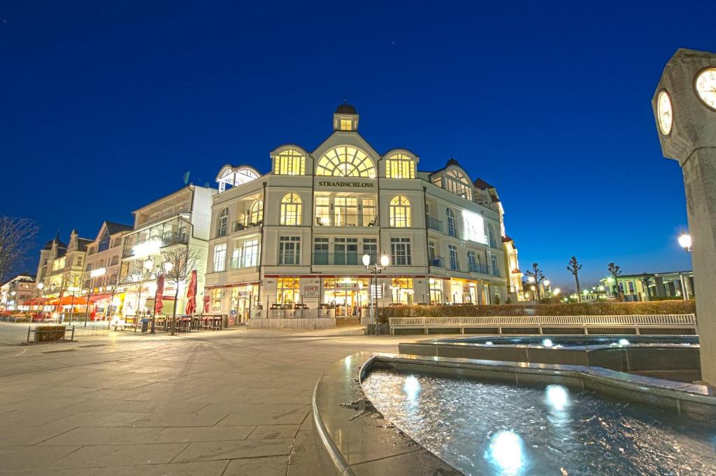 ein großes Gebäude mit einem Uhrturm vor einem Brunnen in der Unterkunft Strandschloss Binz - Penthouse "Royal Beach" mit Sauna, Kamin, Terrasse, Meerblick in Binz