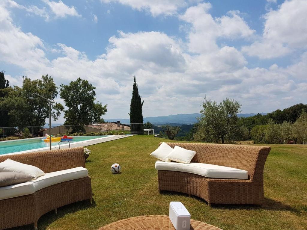 テッラヌオーヴァ・ブラッチョリーニにあるIl Belvedere house in the Tuscan countrysideのプールの近くの芝生に座った籐のソファ2台