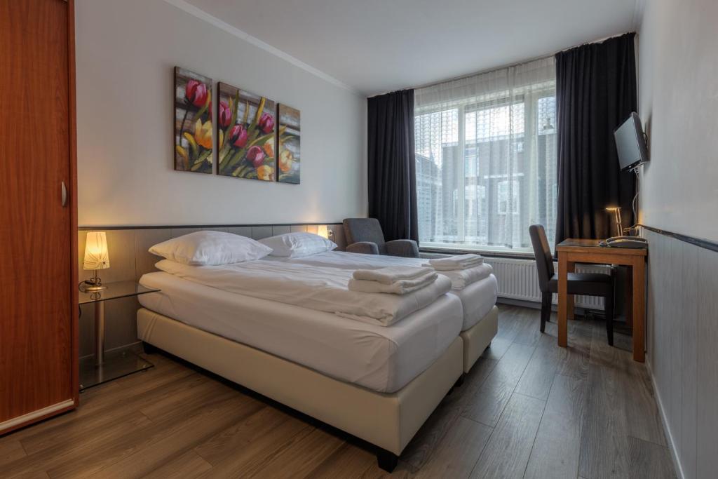 een hotelkamer met een bed, een bureau en een raam bij Hotel Randenbroek in Amersfoort