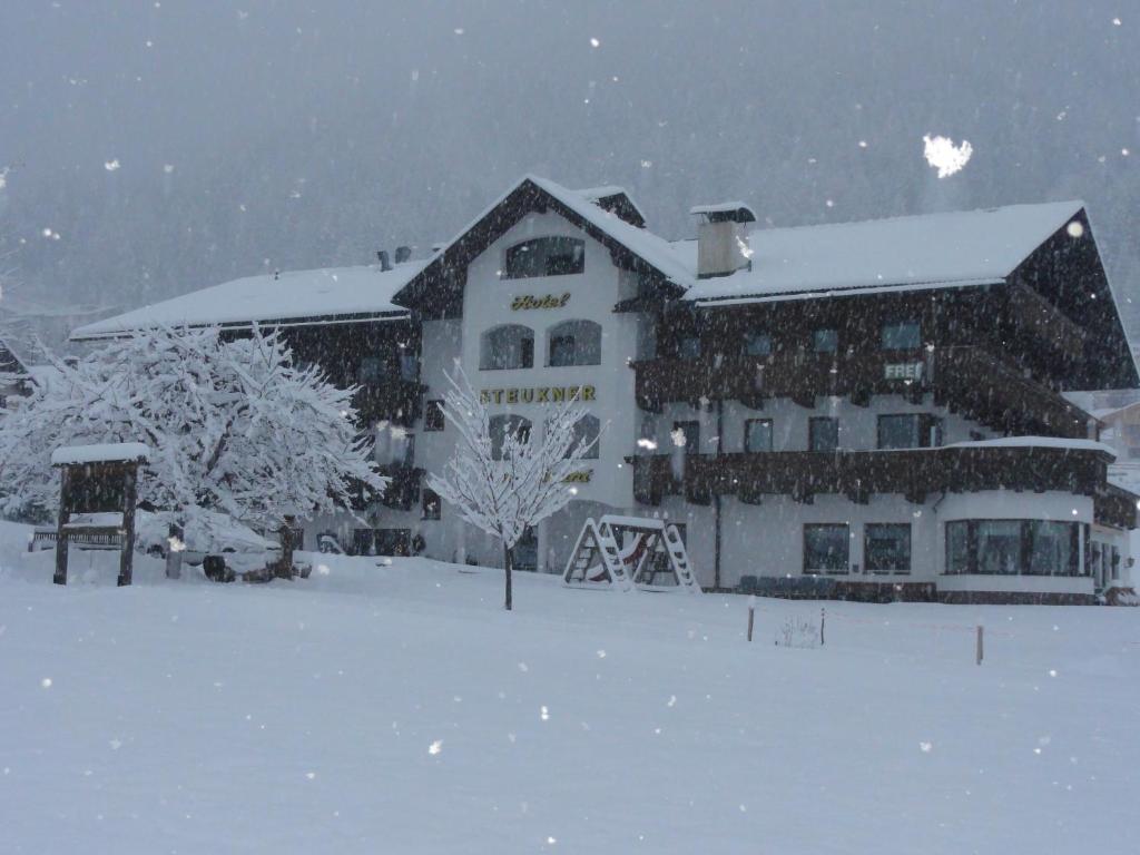duży budynek w śniegu z śniegiem w obiekcie Hotel Steuxner w Neustift im Stubaital