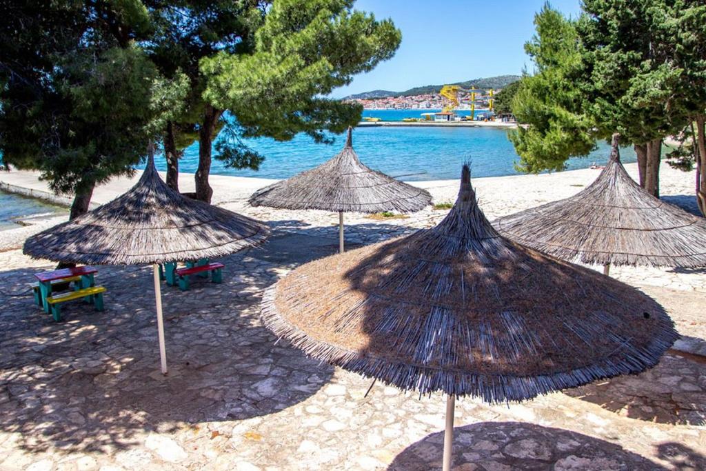 un gruppo di ombrelloni di paglia su una spiaggia di Victoria Mobilehome Camping Imperial a Vodice