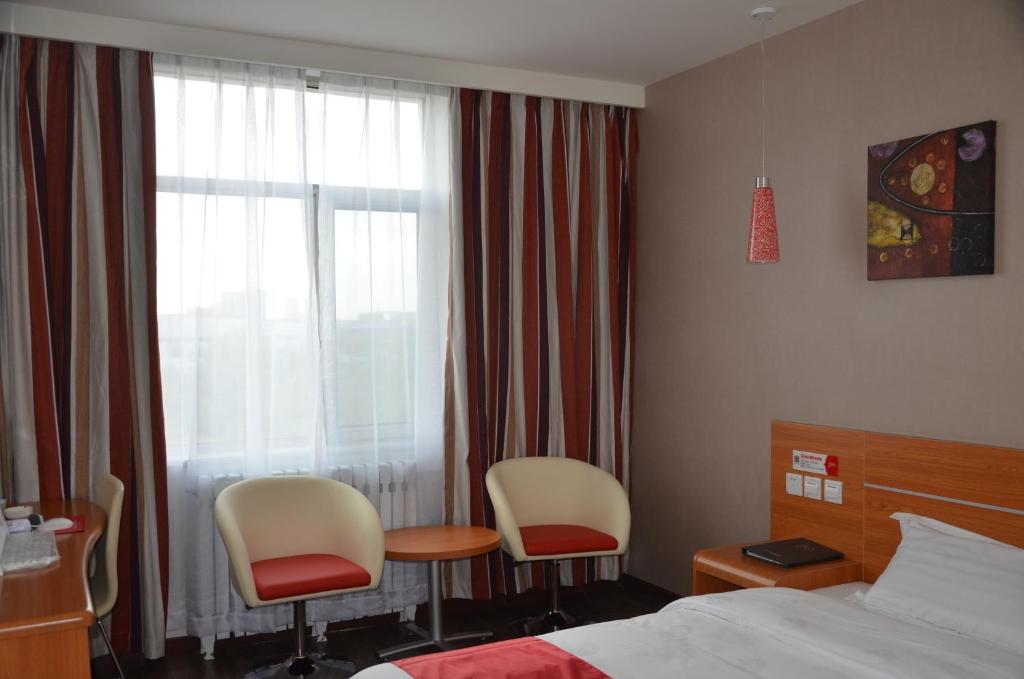 a hotel room with two chairs and a bed and a window at Thank Inn Chain Hotel Gansu Jinchang Heya Road in Pai-chia-tsui