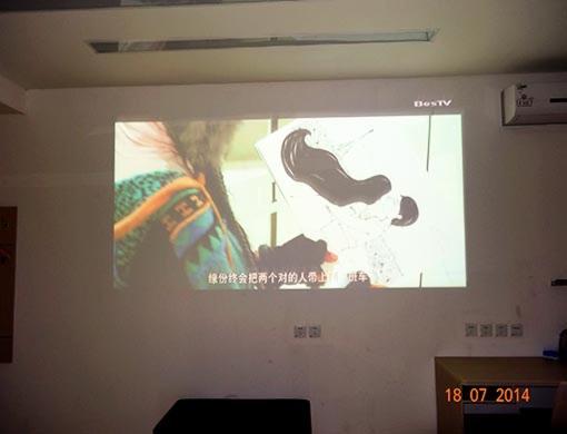 een projectiescherm op een muur met een vrouw erop bij Thank Inn Chain Hotel Gansu Pingliang West Huating Street Zhaozhuang in Khuatin