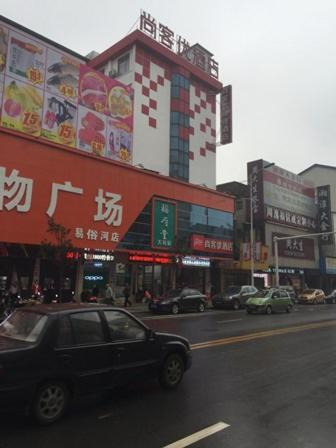 un coche negro conduciendo por una calle de la ciudad con edificios en Thank Inn Chain Hotel Hunan Xiangtan Yisu River, en Xiangtan