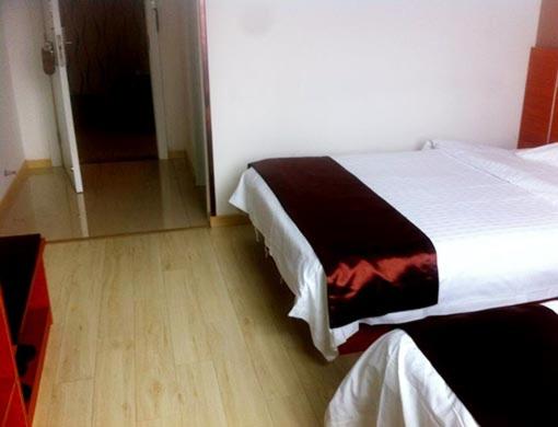 um quarto com 2 camas e piso em madeira em Thank Inn Chain Hotel Jiangsu Yancheng Jianhu Guanhua Road em Jianhu