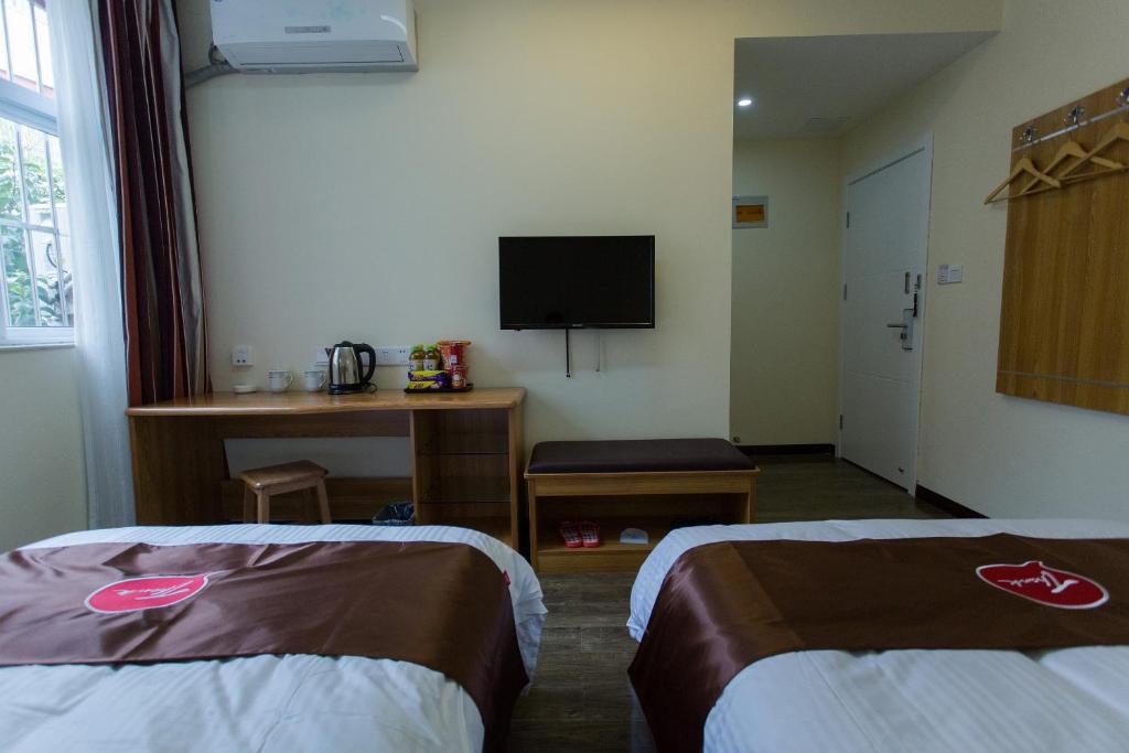 a room with two beds and a flat screen tv at Thank Inn Plus Hotel Henan Luoyan Xigong District Wangcheng Avenue in Luoyang