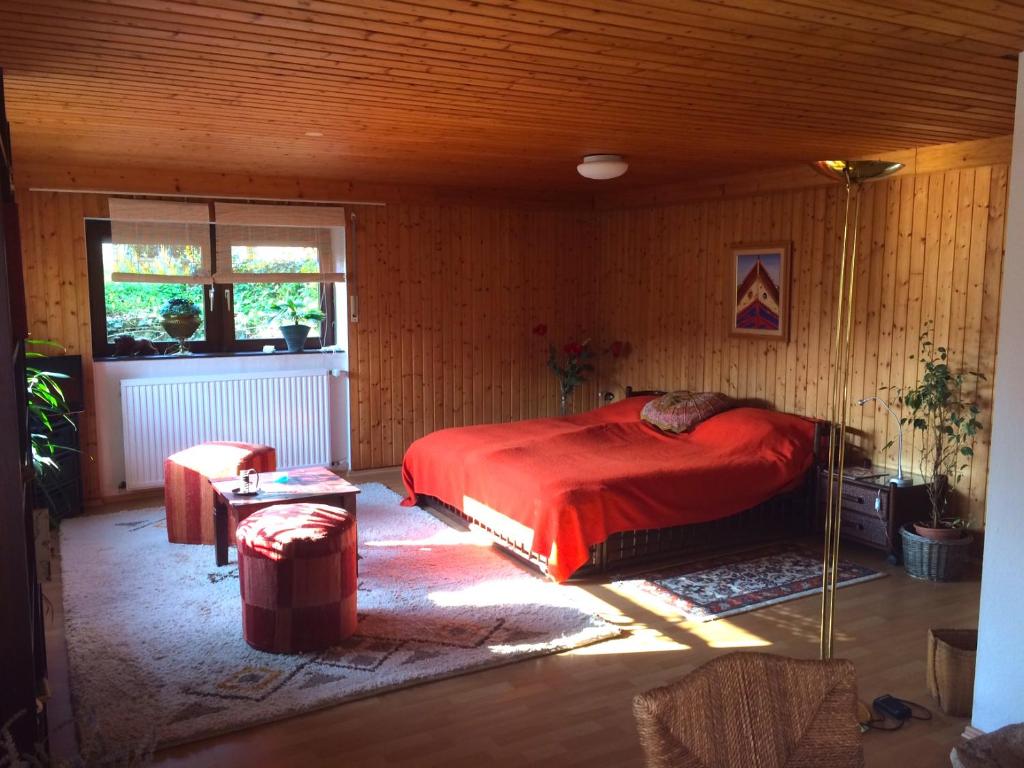 ノイシュタット・アン・デア・ヴァインシュトラーセにあるschones Zimmer in Gimmeldingen/ Konigsbachの木製の部屋に赤いベッドが備わるベッドルーム1室