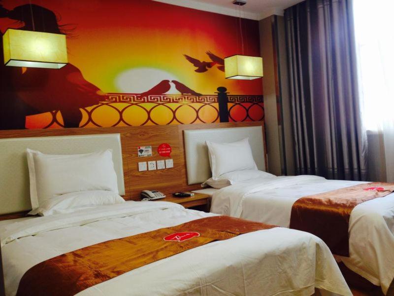 ein Hotelzimmer mit 2 Betten und einem Gemälde an der Wand in der Unterkunft Thank Inn Chain Hotel Henan Xuchang Railway Station Qiyi Road in Xuchang