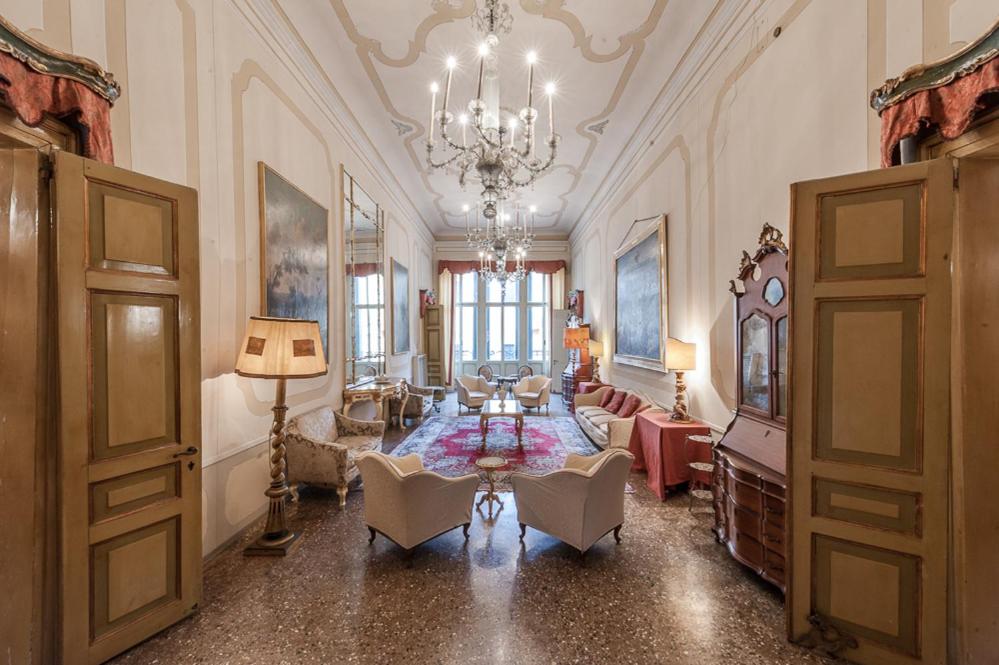 un ampio soggiorno con lampadario a braccio e tavolo di Appartamento Duodo o Barbarigo a Venezia