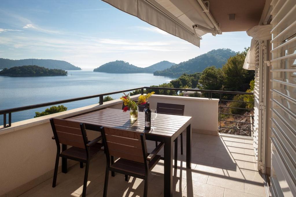 einen Tisch und Stühle auf einem Balkon mit Blick auf das Wasser in der Unterkunft Apartment Pasadur Lastovo in Lastovo