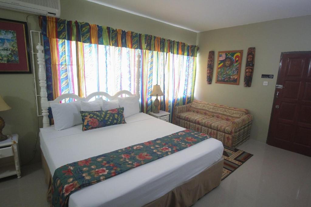 a bedroom with a bed and a chair and a window at Moonrisevillas in Negril