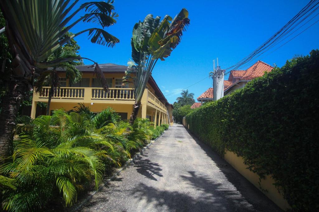 a street with palm trees and a yellow building at Moonrisevillas in Negril