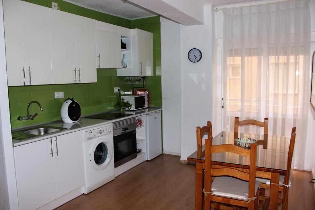 a kitchen with white cabinets and a table and a sink at Apartamento a 5 min de la playa y el centro in Almería