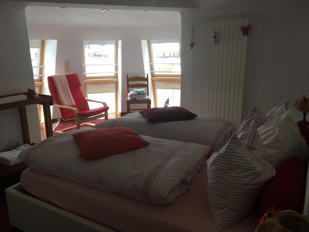 een slaapkamer met 2 bedden, een stoel en ramen bij Villa Alessandra in Colle Isarco