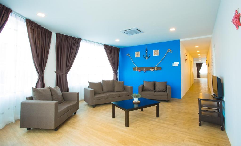 una sala de estar con 2 sofás y una pared azul en Hard Rock VIP Guest House, en Mersing