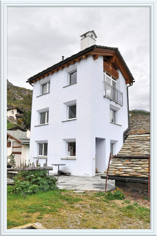 a white building with a roof at Chesa Tre Piz, Maloja in Maloja